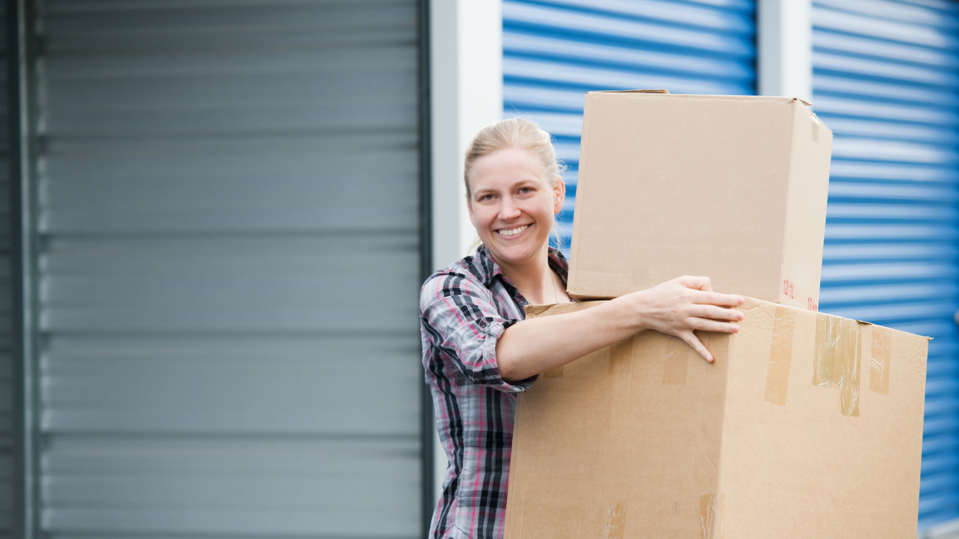 Smiling person carrying cardboard boxes